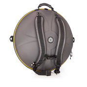 The TurtleCase Handpan Bag Evatek 2.0 medium HCT is a round, hard-shell black case with yellow trim, backpack straps, top handle, and a side zipper pocket for carrying and protecting your handpan or similar instrument.