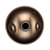 A top-down view of the YataoPan D Kurd 13 by Yatao // Shop, a metallic, round instrument with a central dome and two circular side holes, set against a white background and evoking sleek handpan design.