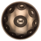 A metallic YataoPan D Kurd 13 handpan drum by Yatao // Shop is shown from above, featuring a central dome, circular indentations, and the brand name engraved near its smooth edge.