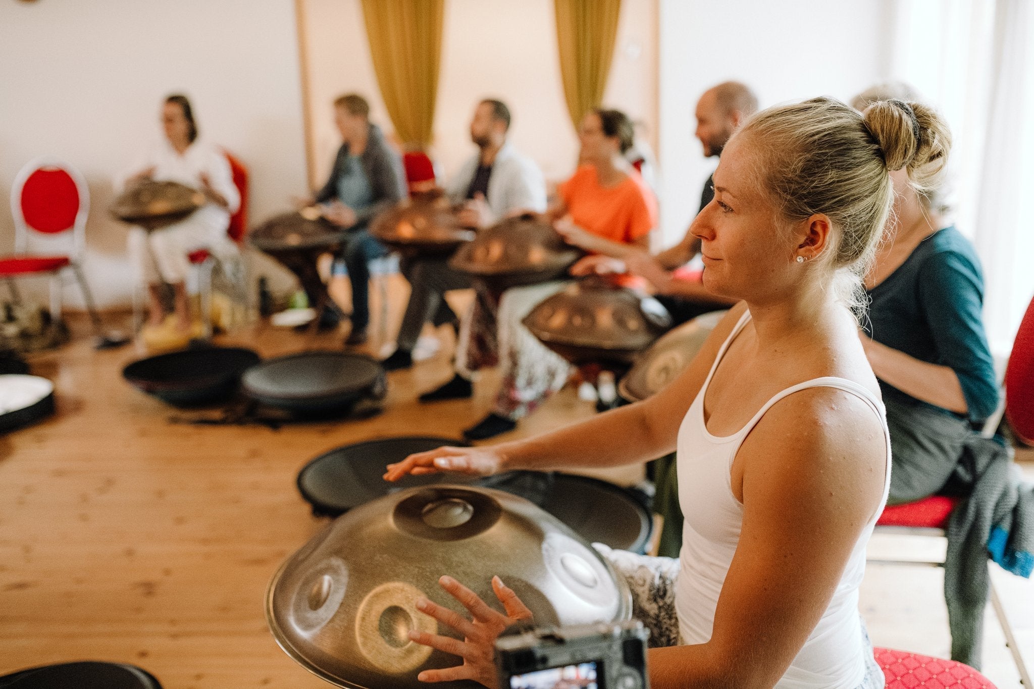 Handpan group course indoors, participants playing together in a bright room
