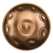 MAG C# Pygmy 17 handpan with 17 notes in a warm gold finish, crafted from Ember Steel, shown from a top-down perspective on a white background
